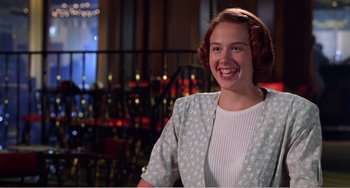 Movie still from “Drop Dead Gorgeous” (1999), directed by Michael Patrick Jann – A young woman smiling for the camera in front of lights; Medium shot, Over the shoulder angle
