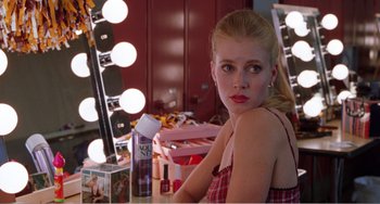 Movie still from “Drop Dead Gorgeous” (1999), directed by Michael Patrick Jann – A woman sitting in front of a mirror with makeup products on the counter; Close Up shot, Over the shoulder angle