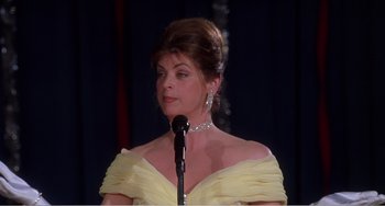 Movie still from “Drop Dead Gorgeous” (1999), directed by Michael Patrick Jann – A woman in a yellow dress standing at a microphone; Medium shot, Low angle