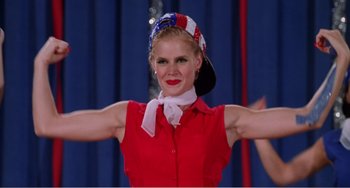 Movie still from “Drop Dead Gorgeous” (1999), directed by Michael Patrick Jann – A woman in a red shirt and a patriotic hat; Medium shot, Low angle