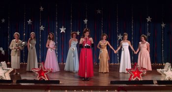 Movie still from “Drop Dead Gorgeous” (1999), directed by Michael Patrick Jann – A group of women on a stage in formal wear; Wide shot, High angle