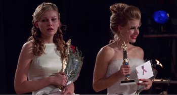 Movie still from “Drop Dead Gorgeous” (1999), directed by Michael Patrick Jann – Two young women in white gowns holding trophies; Medium shot, Low angle