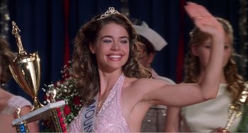 Movie still from “Drop Dead Gorgeous” (1999), directed by Michael Patrick Jann – A woman in a pink dress is smiling for the camera; Close Up shot, Low angle