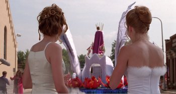 Movie still from “Drop Dead Gorgeous” (1999), directed by Michael Patrick Jann – Two women standing in front of a float in a parade; Wide shot, Low angle
