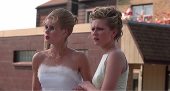 Movie still from “Drop Dead Gorgeous” (1999), directed by Michael Patrick Jann – Two young women standing next to each other in front of a brick building; Close Up shot, Low angle