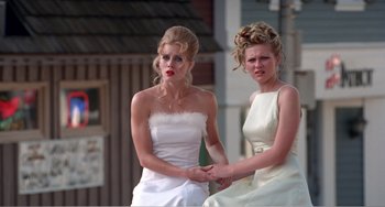 Movie still from “Drop Dead Gorgeous” (1999), directed by Michael Patrick Jann – Two women in wedding dresses holding each other's hands; Medium shot, Low angle