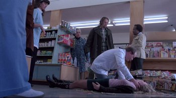 Movie still from “Drugstore Cowboy” (1989), directed by Gus Van Sant – A group of people standing around a man laying on the ground; Wide shot, Low angle