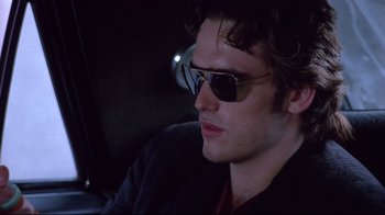 Movie still from “Drugstore Cowboy” (1989), directed by Gus Van Sant – A man wearing sunglasses sitting in the back of a car; Close Up shot, Over the shoulder angle