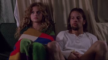 Movie still from “Drugstore Cowboy” (1989), directed by Gus Van Sant – A man and a woman sitting next to each other on a couch; Medium shot, Low angle