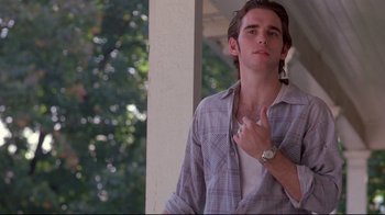 Movie still from “Drugstore Cowboy” (1989), directed by Gus Van Sant – A young man in a plaid shirt is holding his hand up to his chest; Medium shot, Low angle