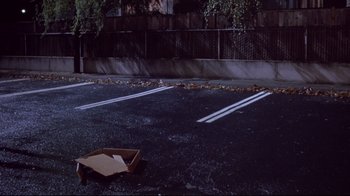 Movie still from “Drugstore Cowboy” (1989), directed by Gus Van Sant – An empty parking lot with a box on the ground; Extreme Wide shot, High angle