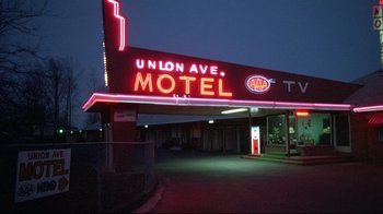 Movie still from “Drugstore Cowboy” (1989), directed by Gus Van Sant – A neon sign is lit up at night in a motel; Wide shot, Low angle