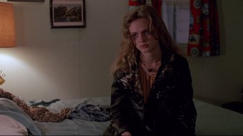 Movie still from “Drugstore Cowboy” (1989), directed by Gus Van Sant – A woman sitting on top of a bed in a room; Medium shot, Over the shoulder angle
