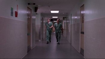 Movie still from “Drugstore Cowboy” (1989), directed by Gus Van Sant – Two men in green scrubs walking down a hall way; Wide shot, Low angle