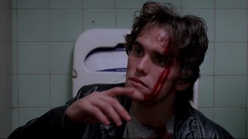 Movie still from “Drugstore Cowboy” (1989), directed by Gus Van Sant – A young man with blood on his face sitting in a bathroom; Close Up shot, High angle
