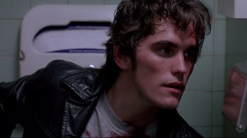 Movie still from “Drugstore Cowboy” (1989), directed by Gus Van Sant – A person wearing a leather jacket; Close Up shot, Over the shoulder angle