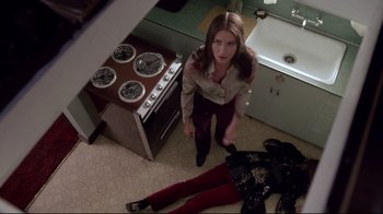 Movie still from “Drugstore Cowboy” (1989), directed by Gus Van Sant – A woman standing over a dead body in a kitchen; Medium shot, Overhead angle