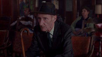 Movie still from “Drugstore Cowboy” (1989), directed by Gus Van Sant – An older man wearing a suit and a hat; Medium shot, Low angle