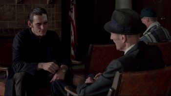 Movie still from “Drugstore Cowboy” (1989), directed by Gus Van Sant – A man in a suit and hat sitting next to another man in a suit; Medium shot, Over the shoulder angle