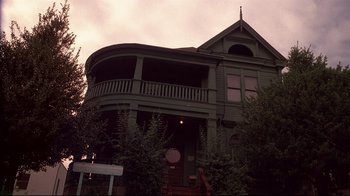 Movie still from “Drugstore Cowboy” (1989), directed by Gus Van Sant – A large green house with a large balcony; Wide shot, Low angle