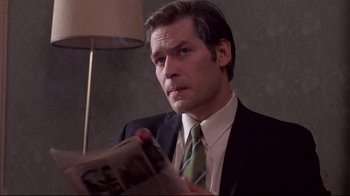 Movie still from “Drugstore Cowboy” (1989), directed by Gus Van Sant – A man wearing a suit and tie holding a newspaper; Close Up shot, Low angle