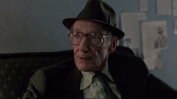 Movie still from “Drugstore Cowboy” (1989), directed by Gus Van Sant – An older man wearing a hat and glasses; Close Up shot, Low angle