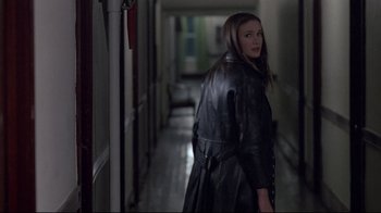 Movie still from “Drugstore Cowboy” (1989), directed by Gus Van Sant – A woman wearing a leather jacket walking down a hall way; Medium shot, Over the shoulder angle