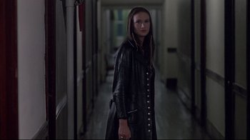 Movie still from “Drugstore Cowboy” (1989), directed by Gus Van Sant – A woman in a black leather jacket standing in a hallway; Medium shot, Over the shoulder angle