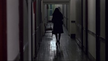Movie still from “Drugstore Cowboy” (1989), directed by Gus Van Sant – A woman walking down a hallway in the dark; Wide shot, Over the shoulder angle