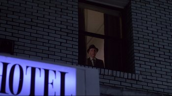 Movie still from “Drugstore Cowboy” (1989), directed by Gus Van Sant – An older man wearing a hat looking out of a window; Wide shot, Low angle
