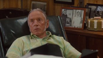 Movie still from “The Paperboy” (2012), directed by Lee Daniels – An older man sitting in a chair in front of a picture; Close Up shot, Over the shoulder angle