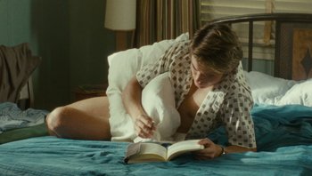 Movie still from “The Paperboy” (2012), directed by Lee Daniels – A woman laying on a bed reading a book; Medium shot, High angle