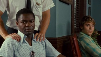 Movie still from “The Paperboy” (2012), directed by Lee Daniels – A man standing next to another man in a room; Close Up shot, Over the shoulder angle