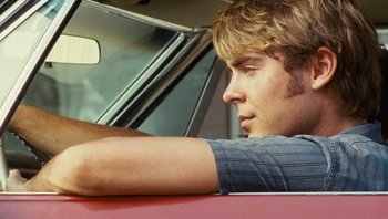 Movie still from “The Paperboy” (2012), directed by Lee Daniels – A man sitting in the driver's seat of a red car; Close Up shot, Over the shoulder angle