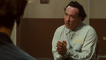 Movie still from “The Paperboy” (2012), directed by Lee Daniels – A man sitting in front of another man in front of a wall; Close Up shot, Over the shoulder angle