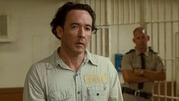 Movie still from “The Paperboy” (2012), directed by Lee Daniels – A man in a jail cell with a badge on his shirt; Close Up shot, Over the shoulder angle
