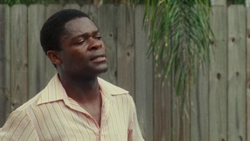 Movie still from “The Paperboy” (2012), directed by Lee Daniels – A man in a striped shirt is standing outside; Close Up shot, Over the shoulder angle