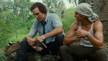 Movie still from “The Paperboy” (2012), directed by Lee Daniels – Two men sitting on the ground near a tree; Medium shot, Low angle