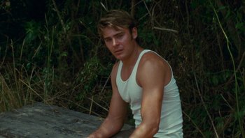 Movie still from “The Paperboy” (2012), directed by Lee Daniels – A man in a white tank top sitting on a wooden bench; Medium shot, Over the shoulder angle