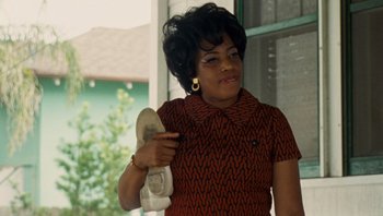 Movie still from “The Paperboy” (2012), directed by Lee Daniels – An older woman holding a pair of white shoes; Medium shot, Low angle