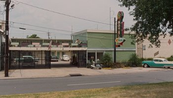 Movie still from “The Paperboy” (2012), directed by Lee Daniels – A green motel with a sign that reads " motel " on it's side; Extreme Wide shot, Low angle