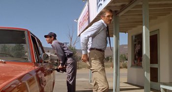 Movie still from “Duel” (1971), directed by Steven Spielberg – A man standing next to another man next to a car; Wide shot, Low angle