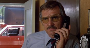 Movie still from “Duel” (1971), directed by Steven Spielberg – An older man wearing glasses talking on a phone; Close Up shot, Low angle
