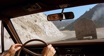 Movie still from “Duel” (1971), directed by Steven Spielberg – A man driving a car down a mountain side road; Wide shot, High angle