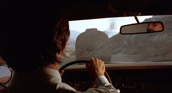 Movie still from “Duel” (1971), directed by Steven Spielberg – A man driving a car in the middle of the road; Medium shot, Over the shoulder angle