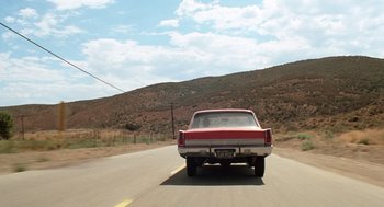 Movie still from “Duel” (1971), directed by Steven Spielberg – A car driving down a road near a mountain; Extreme Wide shot, Low angle