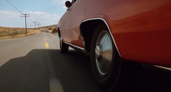 Movie still from “Duel” (1971), directed by Steven Spielberg – View of the wheels of a red car; Wide shot, Low angle