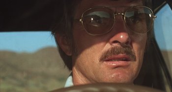 Movie still from “Duel” (1971), directed by Steven Spielberg – A person wearing a hat and glasses; Close Up shot, Low angle