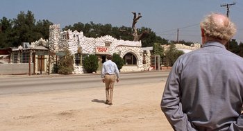 Movie still from “Duel” (1971), directed by Steven Spielberg – A man walking down the street in front of a building; Wide shot, Over the shoulder angle