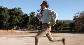 Movie still from “Duel” (1971), directed by Steven Spielberg – A man running in the dirt with trees in the background; Wide shot, Low angle